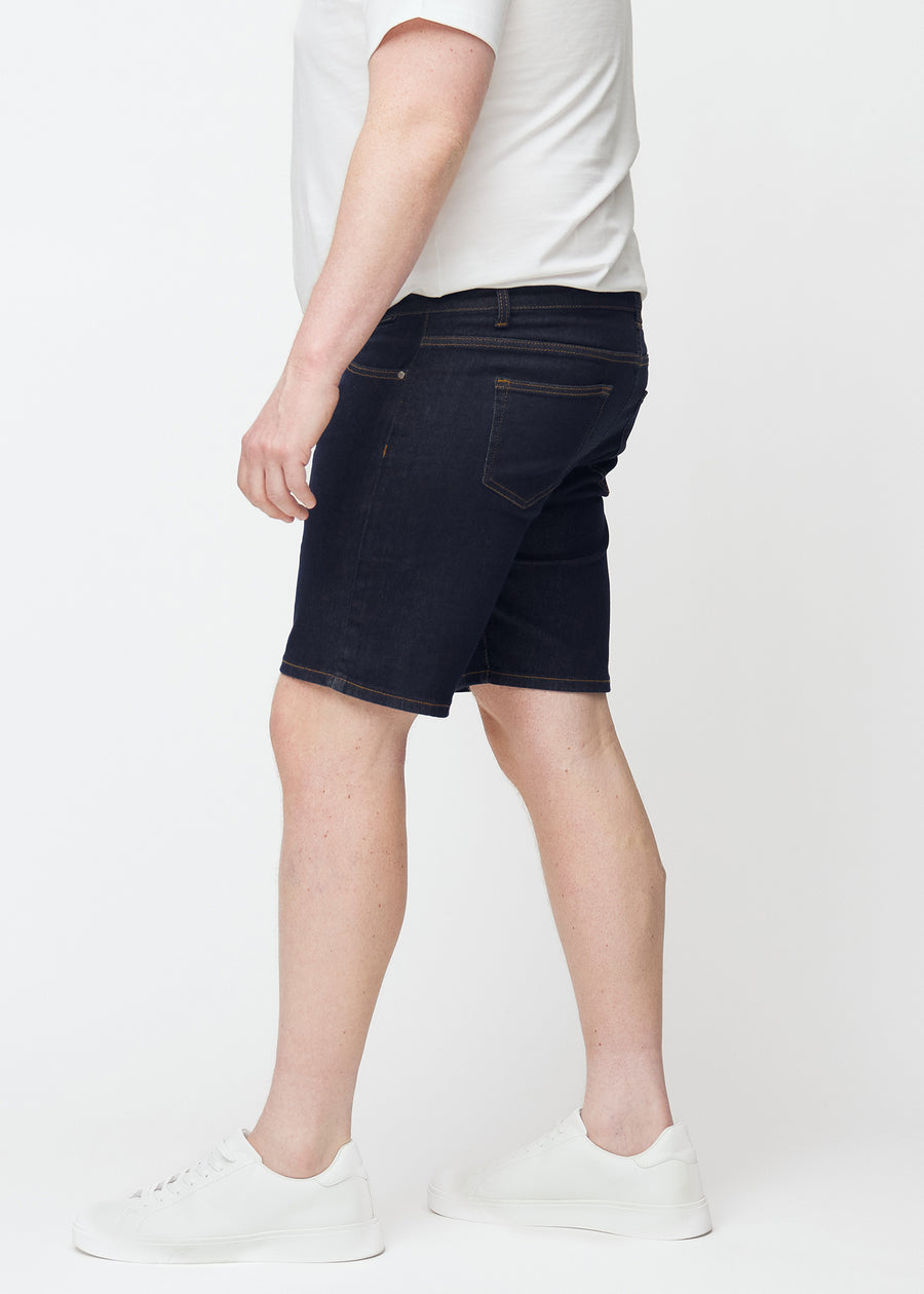 Dyp mørkeblå denimshorts til herre i fargen Midnights med slim passform sett fra siden på plus-size modell.
