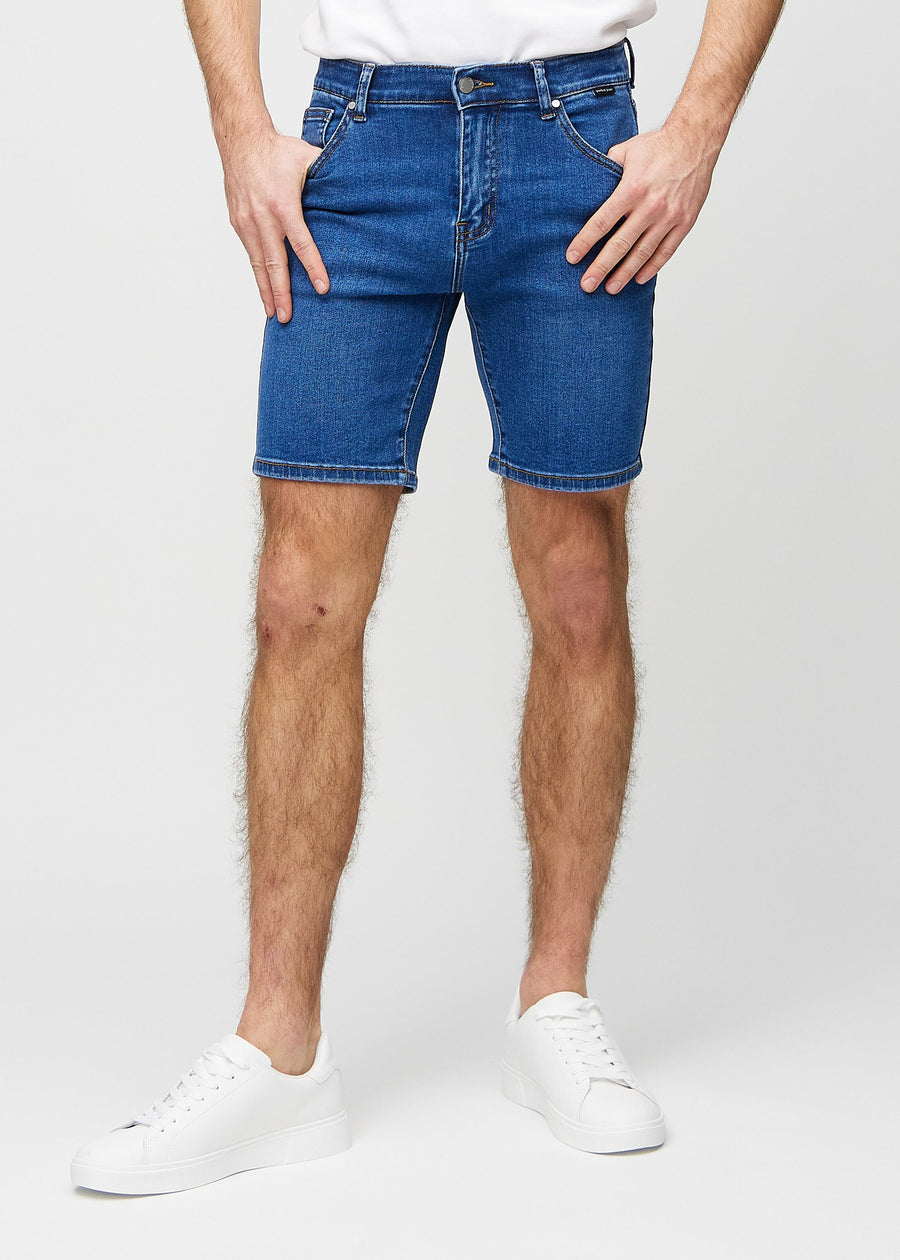 Mørke denim middle-slim shorts, som sitter rett langs låret og slutter rett over kneet, sett forfra.
