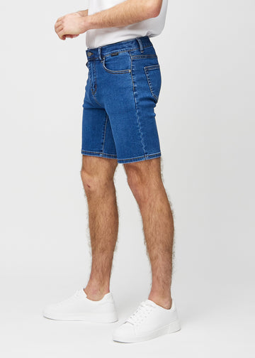 Mørke denim middle-slim shorts sett fra siden på modell.