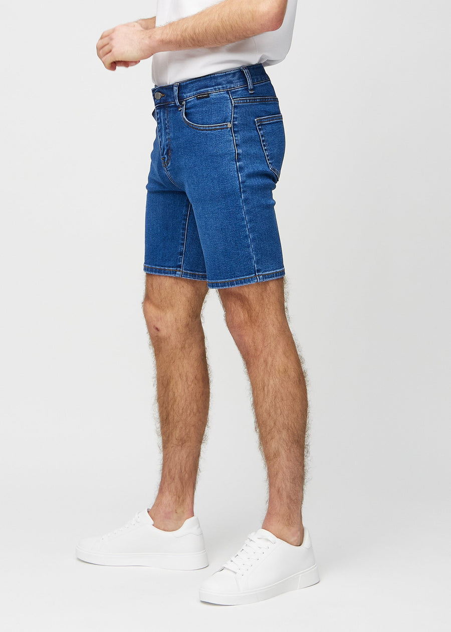 Mørke denim middle-slim shorts sett fra siden på modell.