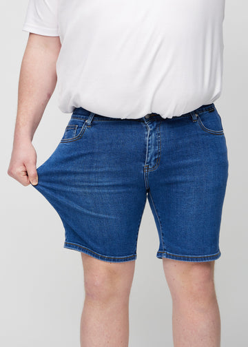 Plus-size-modellen strekker shortsene ved låret for å vise stretch.