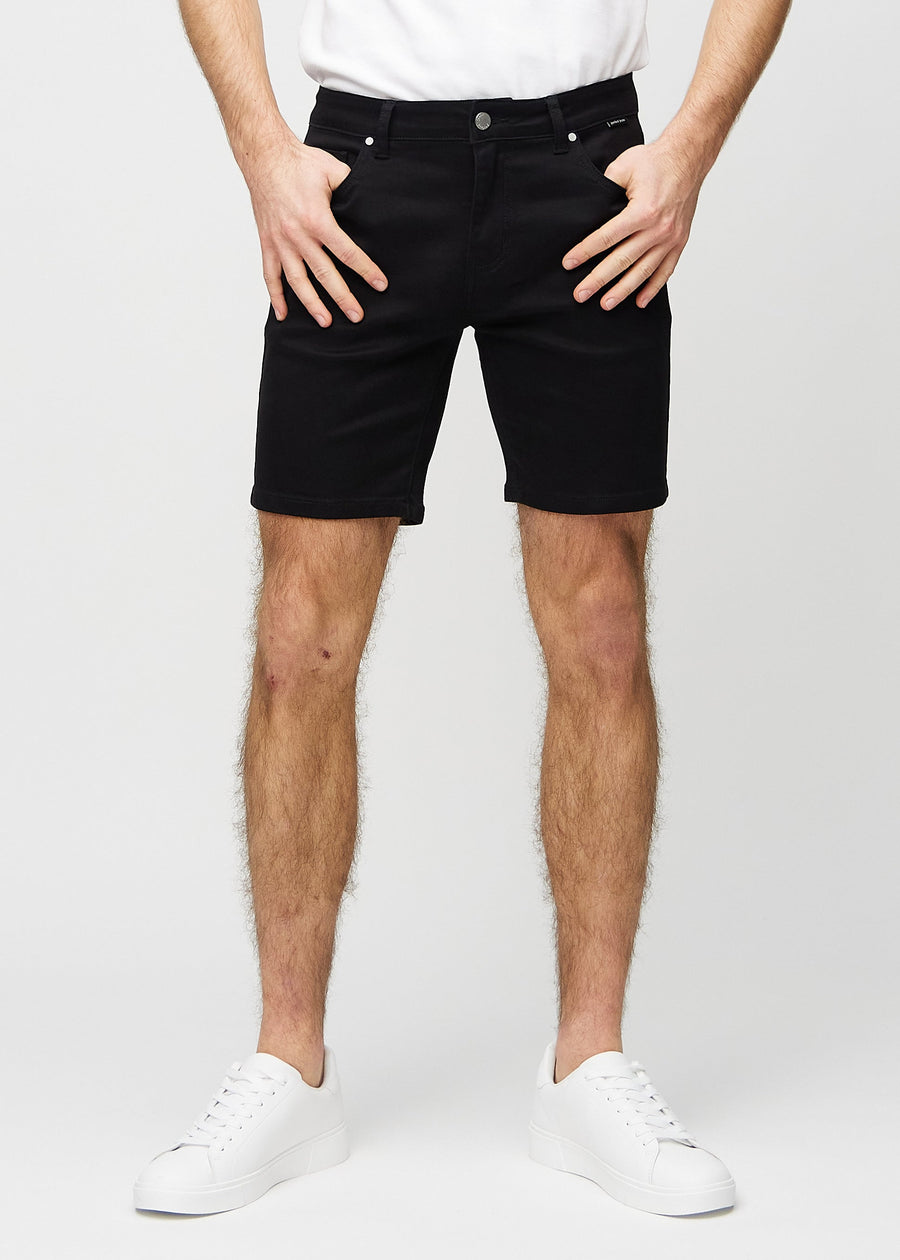 Svarte middle-slim shorts, som sitter rett langs låret og slutter rett over kneet, sett forfra.