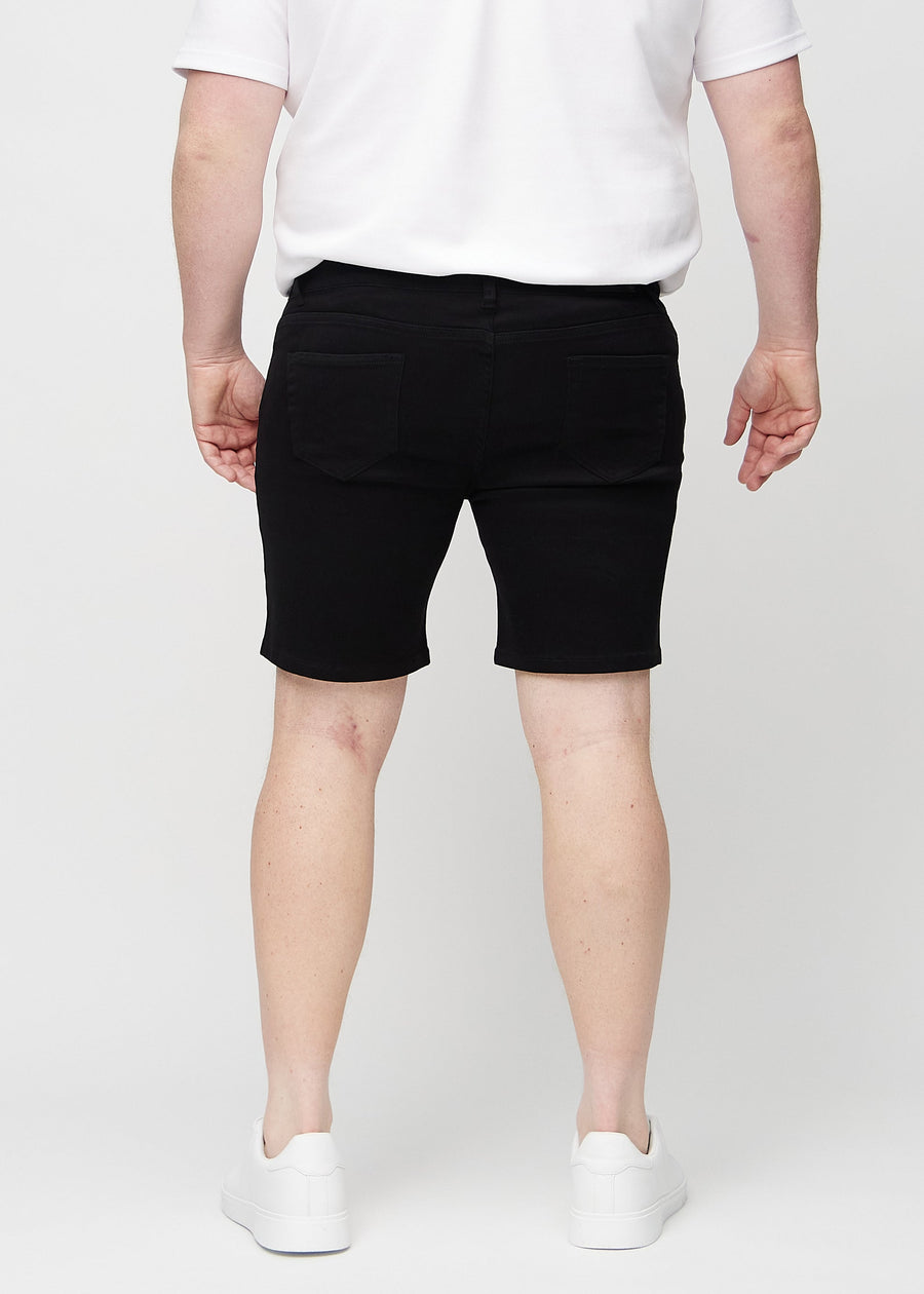 Svarte middle-slim shorts sett bakfra på en plus-size-modell, så man kan se hele produktet.