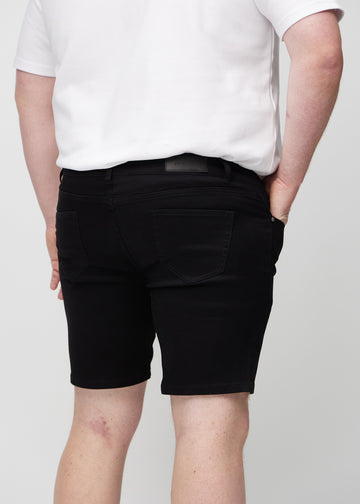 Svarte middle-slim shorts sett bakfra på nært hold på en plus-size-modell for å vise detaljer.