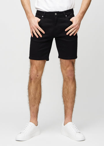 Svarte middle-slim shorts, som sitter rett langs låret og slutter rett over kneet, sett forfra.