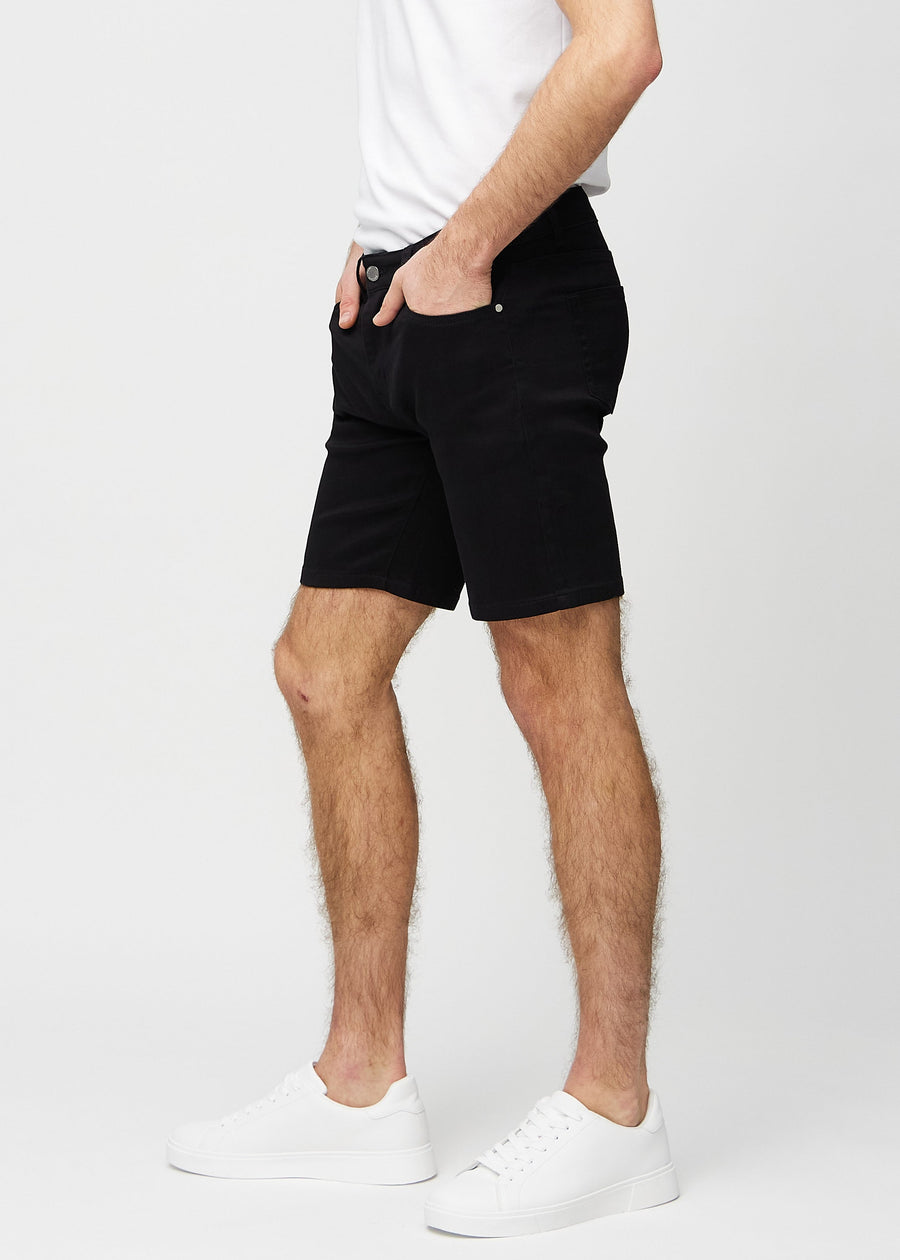 Svarte middle-slim shorts sett fra siden på modell.