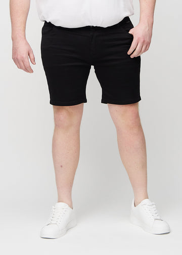 Svarte middle-slim shorts, som sitter rett langs låret og slutter rett over kneet på en plus-size-modell, sett forfra.