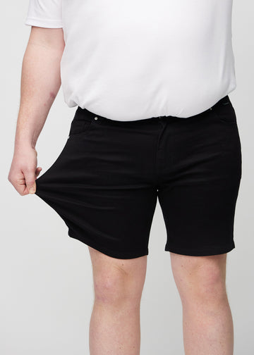 Plus-size-modellen strekker shortsen ved låret for å vise stretch.