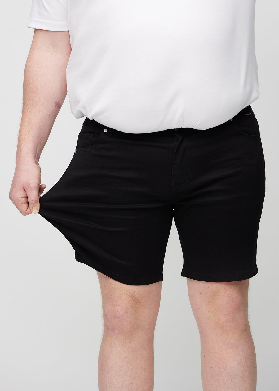 Plus-size-modellen strekker shortsen ved låret for å vise stretch.