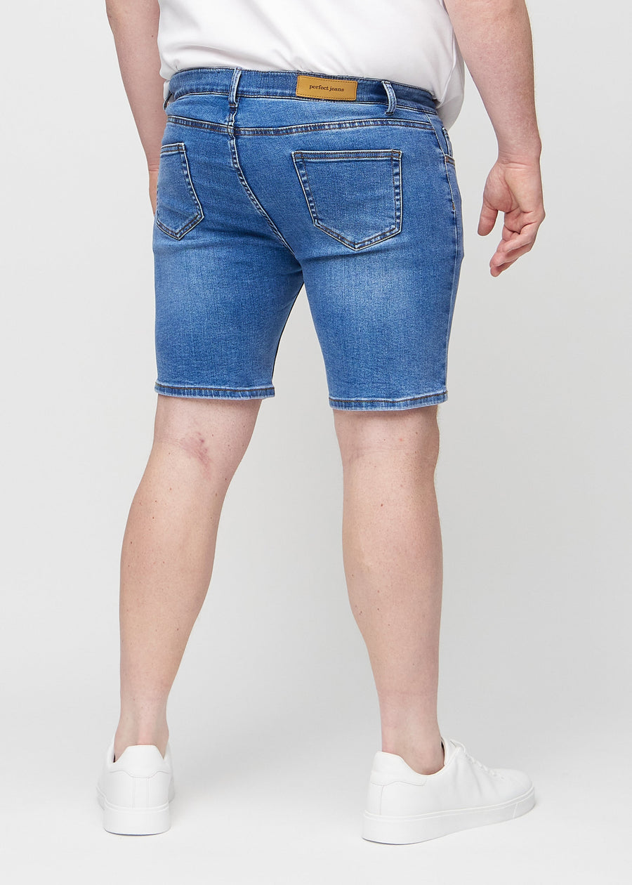 Denim middle-slim shorts sett bakfra på en plus-size-modell, slik at man kan se hele produktet.