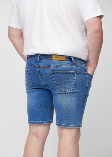 Denim middle-slim shorts sett bakfra på nært hold på en plus-size-modell for å vise detaljer.