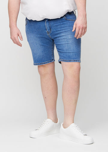 Denim middle-slim shorts, som sitter rett langs låret og slutter rett over kneet på en plus-size-modell, sett forfra.