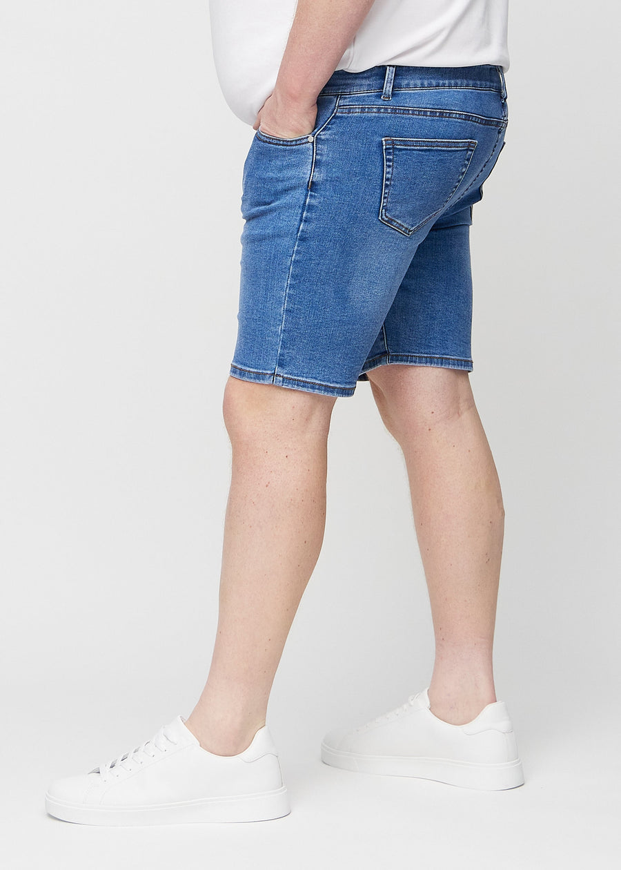 Denim middle-slim shorts sett fra siden på en plus-size-modell.