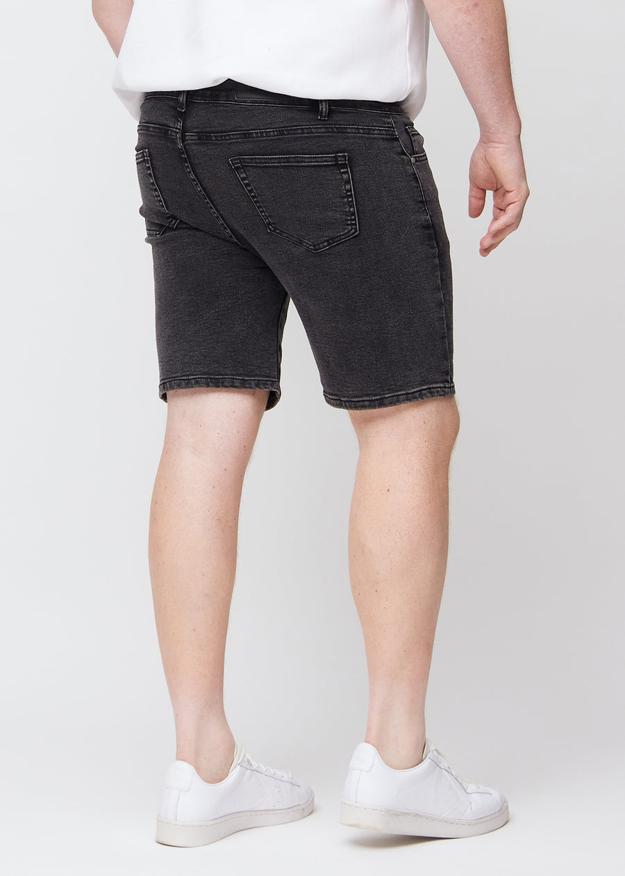 Mørkegrå denim middle-slim shorts sett bakfra på en plus-size-modell, slik at man kan se hele produktet.