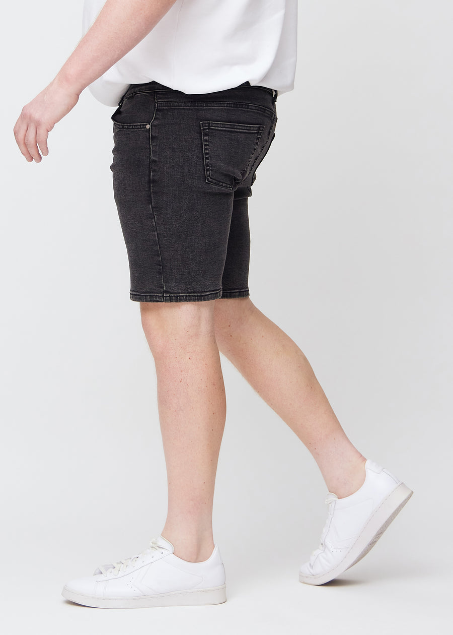 Mørkegrå denim middle-slim shorts sett fra siden på en plus-size-modell.