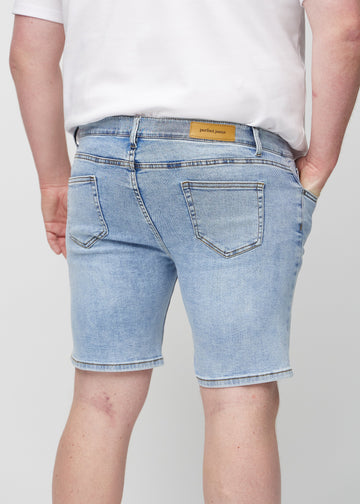 Lys denim middle-slim shorts sett bakfra på nært hold på en plus-size-modell for å vise detaljer.