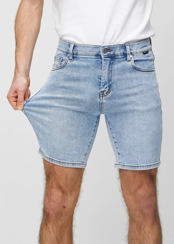Modellen strekker shortsen ved låret for å vise stretch.