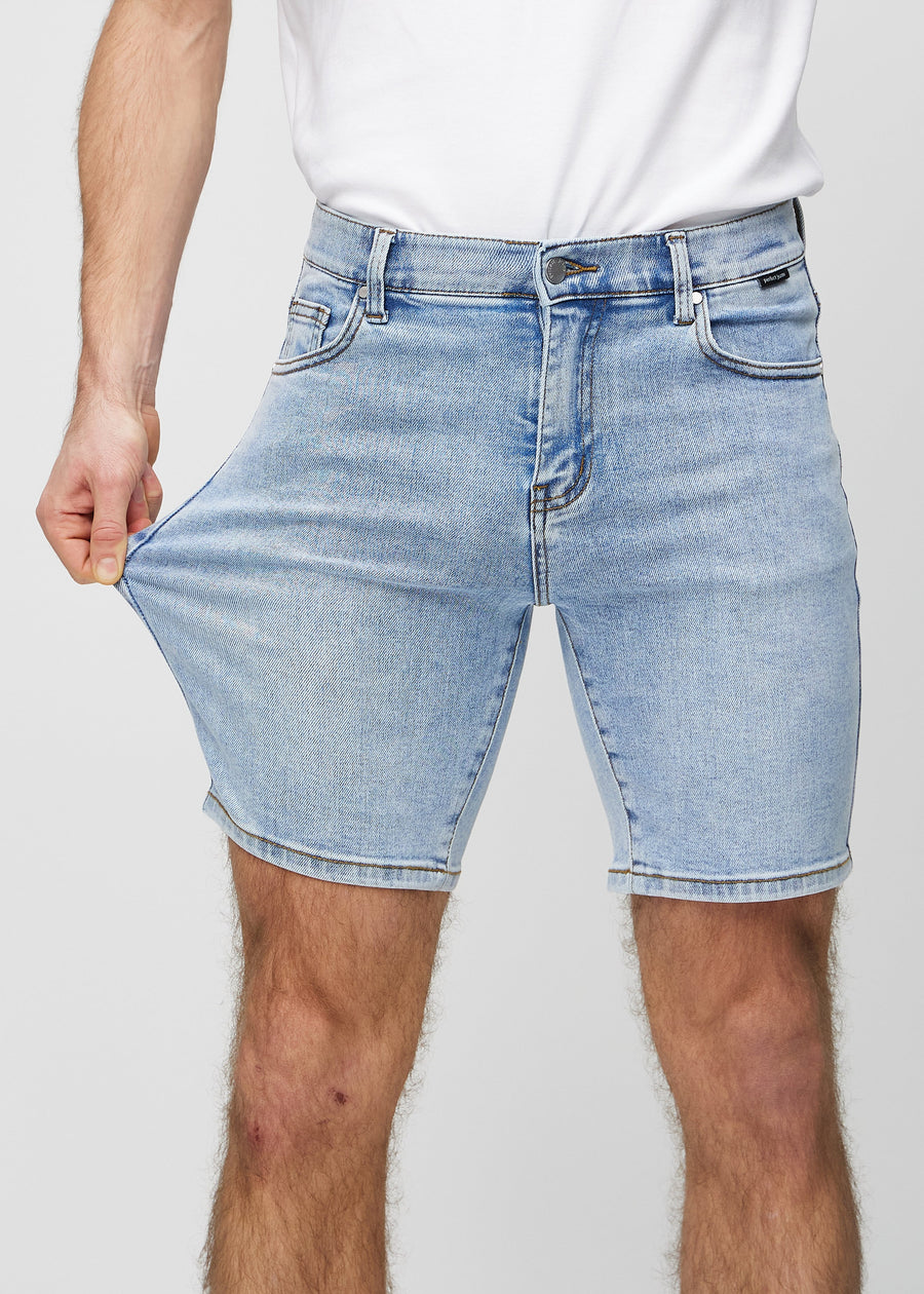 Modellen strekker shortsen ved låret for å vise stretch.