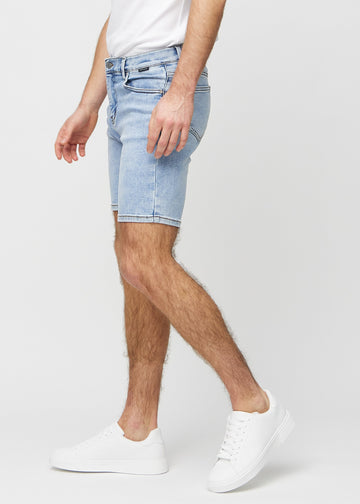 Lys denim middle-slim shorts sett fra siden på modell.