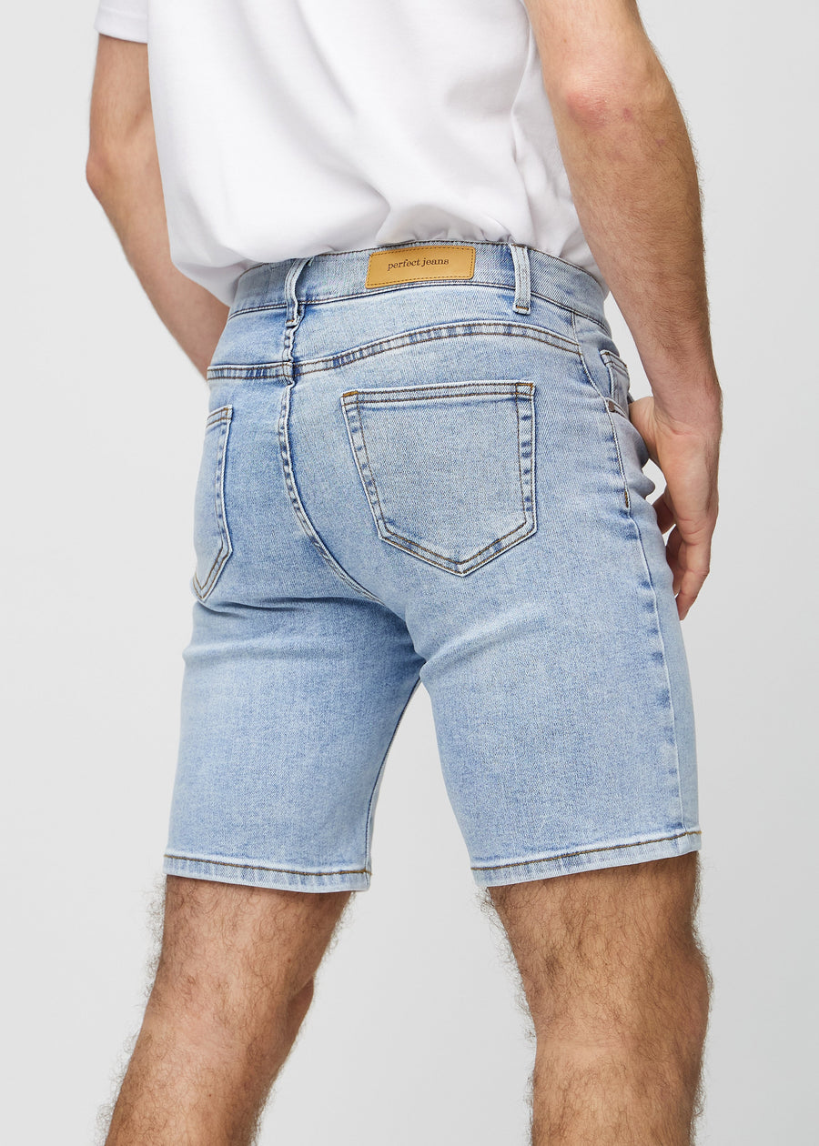 Lys denim middle-slim shorts sett bakfra på nært hold for å vise detaljer.