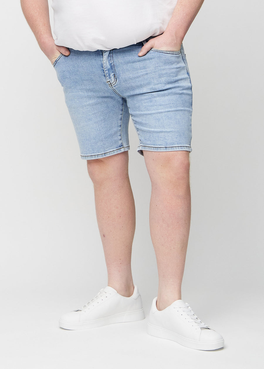 Lys denim middle-slim shorts, som sitter rett langs låret og slutter rett over kneet på en plus-size-modell, sett forfra.