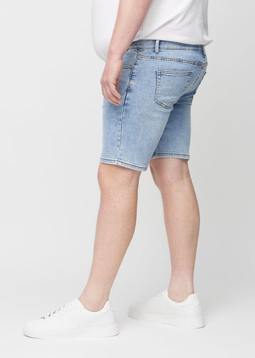 Lys denim middle-slim shorts sett fra siden på en plus-size-modell.