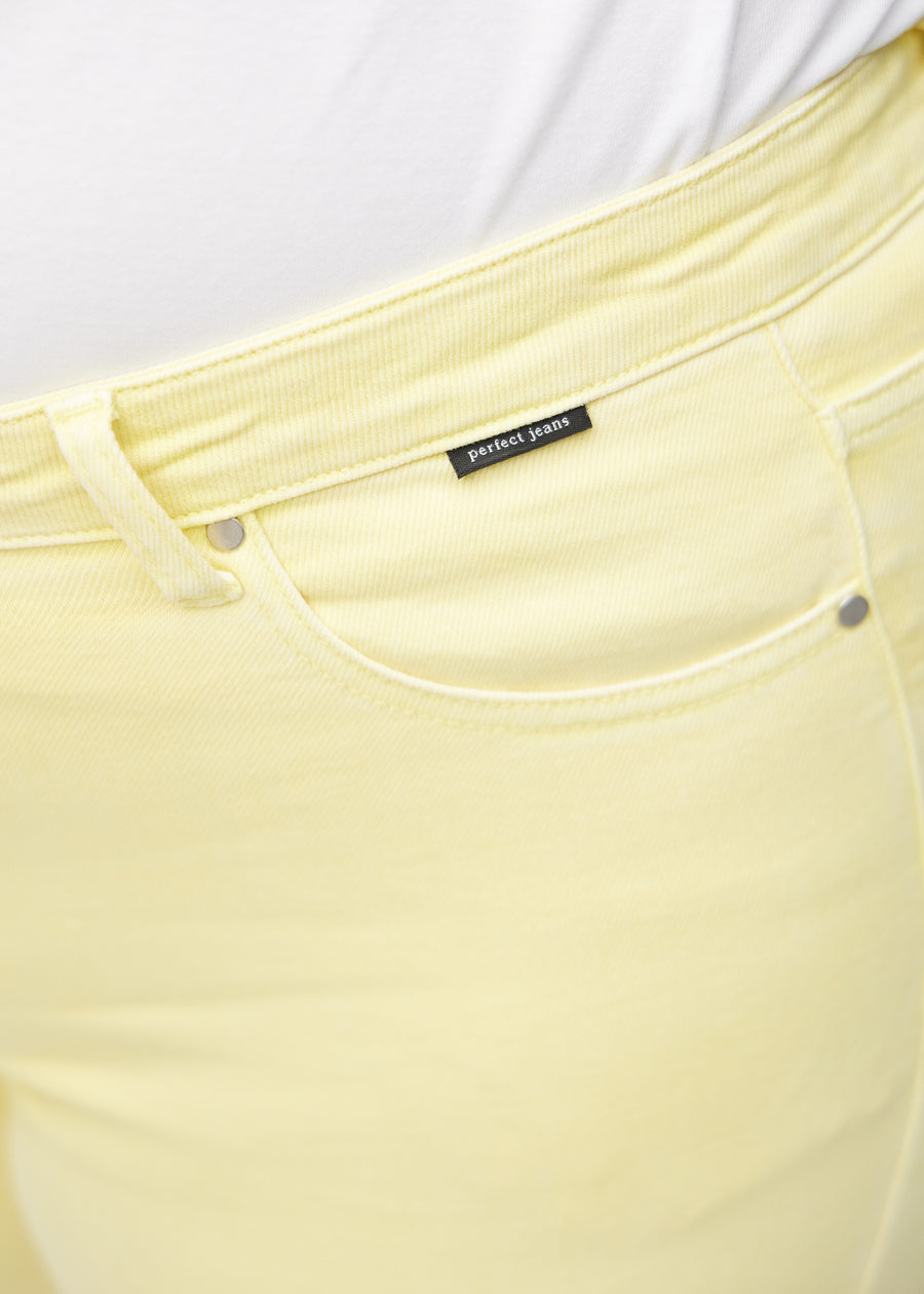 Forlommen på et par lysegule skinny capris, hvor man kan se logoet på en plus-size model.