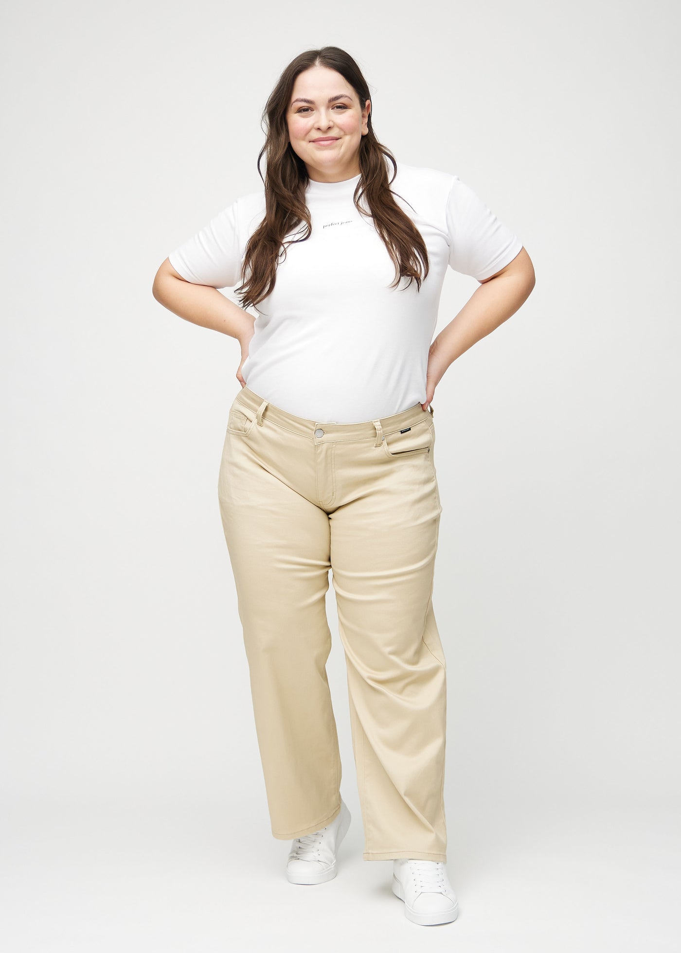 Plus-size model går ind i billedet, strækker i jeansene, viser dem frem ved at dreje rundt, og forlader derefter billedet.