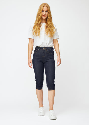 Model viser dyb mørkeblå denim capris til kvinder i farven Midnights med slim pasform i bevægelse.