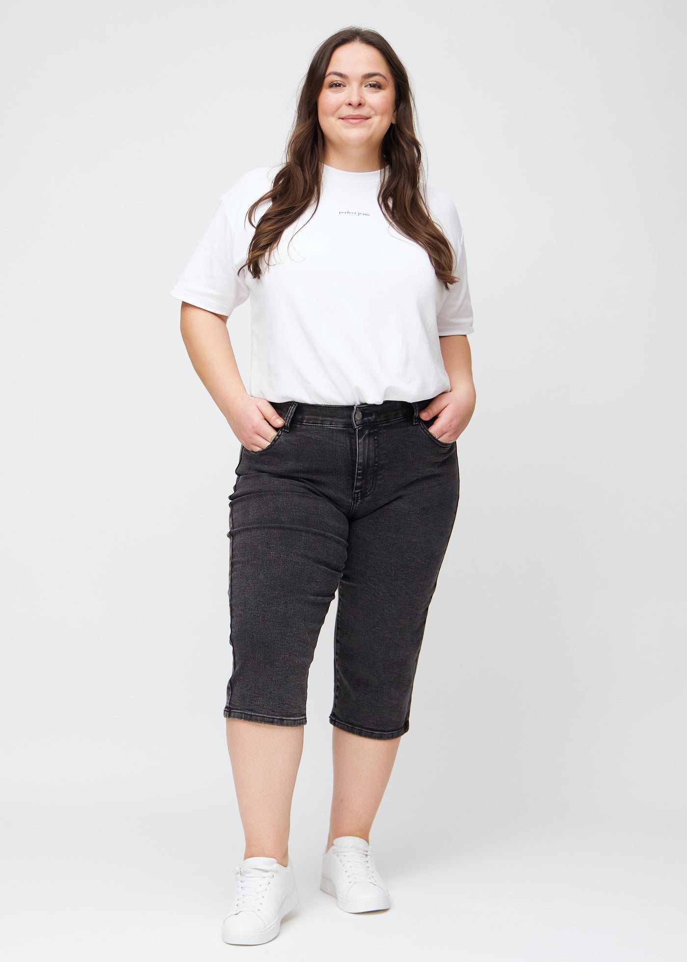 Plus-size model går ind i billedet, strækker i sine capris, viser dem frem ved at dreje rundt, og forlader derefter billedet.