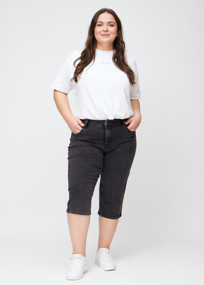 Plus-size model går ind i billedet, strækker i sine capris, viser dem frem ved at dreje rundt, og forlader derefter billedet.