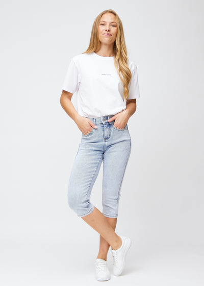 Model træder ind i billedet, strækker i sine lyseblå denim slim capris, viser dem frem ved at dreje rundt, og går derefter ud af billedet igen.