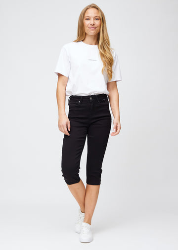 Model træder ind i billedet, strækker i sine sorte slim capris, viser dem frem ved at dreje rundt, og går derefter ud af billedet igen.